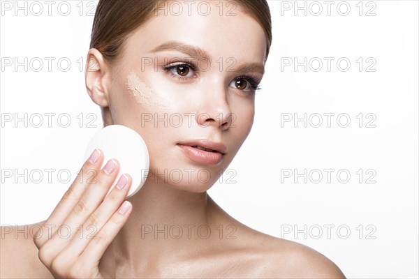 Beautiful young girl with sponge for application make-up and French manicure. Beauty face. Picture taken in the studio on a white background