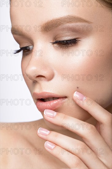 Beautiful young girl with a light natural make-up and French manicure. Beauty face. Picture taken in the studio on a white background