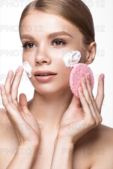 Beautiful young girl with sponge and foam cleanser and French manicure. Beauty face. Picture taken in the studio on a white background