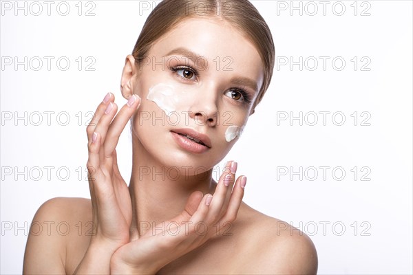 Beautiful young girl with cream on the skin and French manicure. Beauty face. Picture taken in the studio on a white background