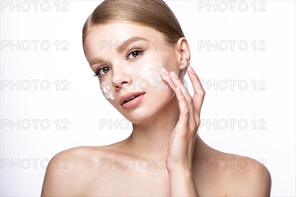 Beautiful young girl with cream on the skin and French manicure. Beauty face. Picture taken in the studio on a white background