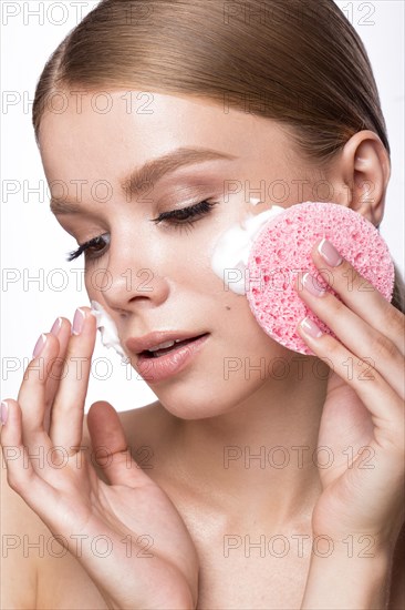 Beautiful young girl with sponge and foam cleanser and French manicure. Beauty face. Picture taken in the studio on a white background