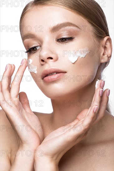 Beautiful young girl with cream on the skin and French manicure. Beauty face. Picture taken in the studio on a white background