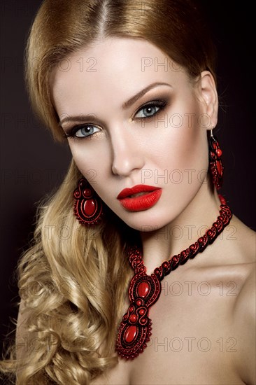 Beautiful blonde woman with evening make-up and red lips. Picture taken in the studio on a black background