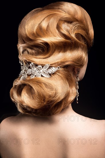 Beautiful red-haired girl in a black dress with a smooth evening haircut in the form of waves and bright makeup. Beauty face. Picture taken in the studio on a black background