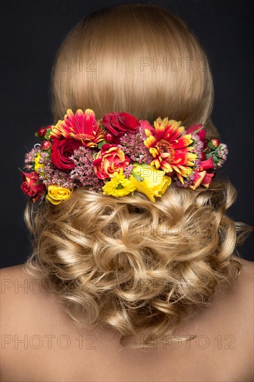 Portrait of a beautiful blond woman in the image of the bride with flowers in her hair. Picture taken in the studio on a black background. Beauty face and Hairstyle back view