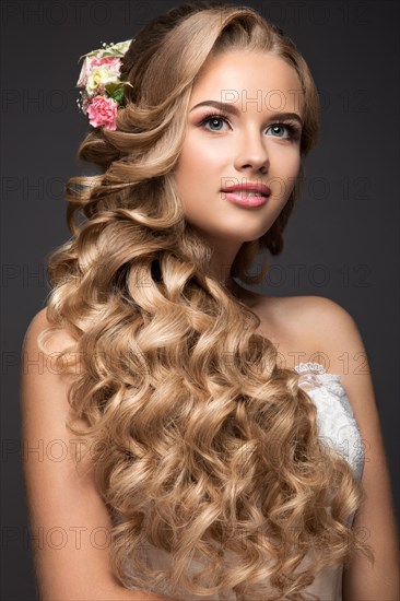 Portrait of a beautiful blond woman in the image of the bride with flowers in her hair. Picture taken in the studio on a black background. Beauty face and Hairstyle