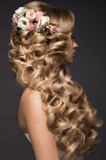 Portrait of a beautiful blond woman in the image of the bride with flowers in her hair. Picture taken in the studio on a black background. Beauty face and Hairstyle