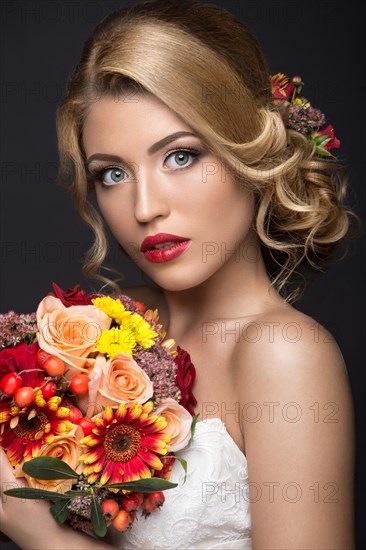 Portrait of a beautiful blond woman in the image of the bride with flowers in her hair. Picture taken in the studio on a black background. Beauty face and Hairstyle