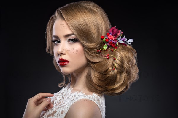 Portrait of a beautiful blond girl in image of the bride with purple flowers on her head. Beauty face. Photo shot in the Studio on a grey background