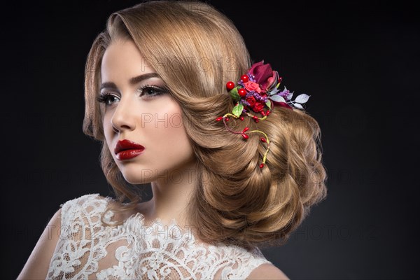 Portrait of a beautiful blond girl in image of the bride with purple flowers on her head. Beauty face. Photo shot in the Studio on a grey background