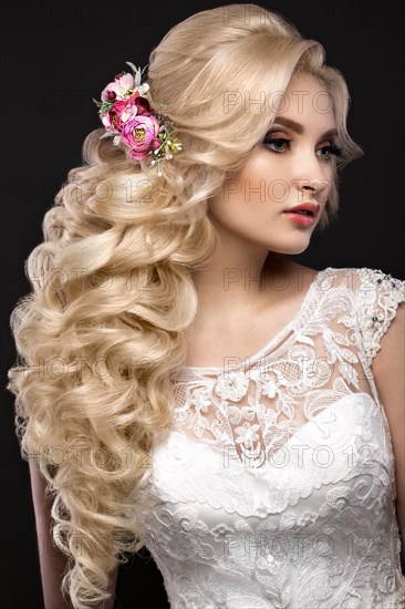 Portrait of a beautiful blond girl in image of the bride with purple flowers on her head. Beauty face. Photo shot in the Studio on a grey background