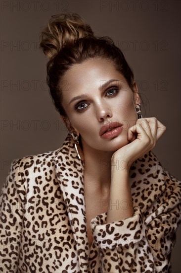 Beautiful sexy woman in a leopard coat and earrings