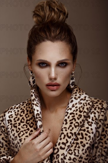 Beautiful sexy woman in a leopard coat and earrings