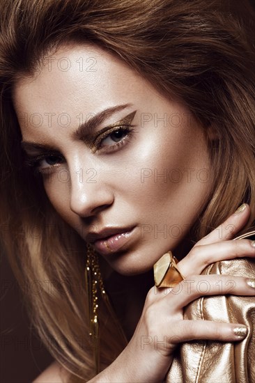 Beautiful girl in a gold dress with creative makeup and hair. The beauty of the face. Photos shot in the studio