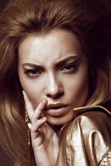 Beautiful girl in a gold dress with creative makeup and hair. The beauty of the face. Photos shot in the studio