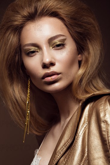 Beautiful girl in a gold dress with creative makeup and hair. The beauty of the face. Photos shot in the studio