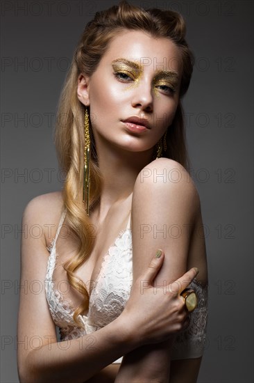 Beautiful girl in Underwear with creative gold makeup and hair. The beauty of the face. Photos shot in the studio