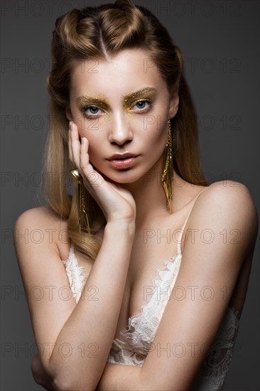 Beautiful girl in Underwear with creative gold makeup and hair. The beauty of the face. Photos shot in the studio