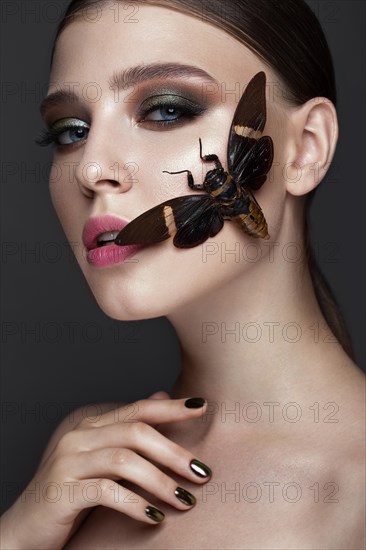 Portrait of beautiful girl with colorful make-up and cicada. Beauty face. Photo taken in the studio