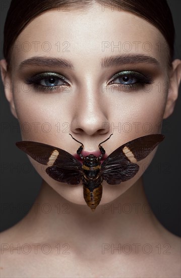 Portrait of beautiful girl with colorful make-up and cicada. Beauty face. Photo taken in the studio