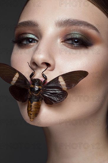 Portrait of beautiful girl with colorful make-up and cicada. Beauty face. Photo taken in the studio