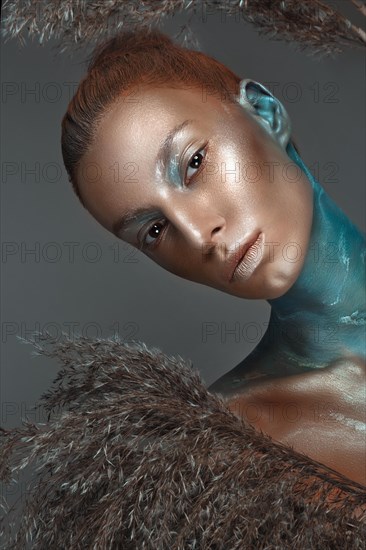 Portrait of a girl with gold and blue creative art make-up. Photo taken in the studio