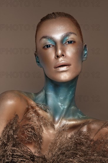 Portrait of a girl with gold and blue creative art make-up. Photo taken in the studio