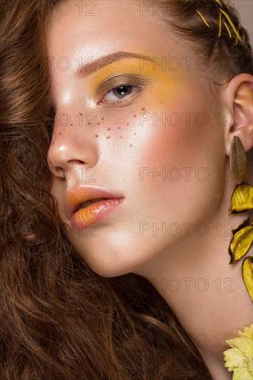 Portrait of beautiful red-haired girl with brightly colored art makeup and curls. Beauty face. Photo taken in the studio