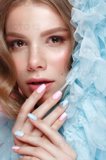 Beautiful girl with light make-up and gentle manicure in blue clothes. Beauty face. Design nails. Photo taken in studio on pink background