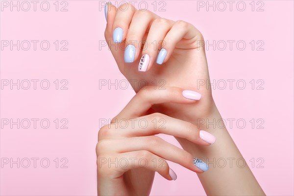 Beautiful pink and blue manicure with crystals on female hand. Close-up. Picture taken in the studio