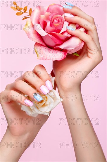 Beautiful pink and blue manicure with crystals on female hand. Close-up. Picture taken in the studio