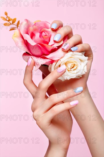 Beautiful pink and blue manicure with crystals on female hand. Close-up. Picture taken in the studio