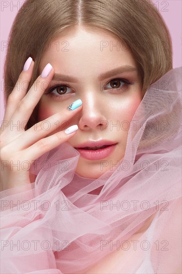 Beautiful girl with light make-up and gentle manicure in pink clothes. Beauty face. Design nails. Photo taken in studio on pink background