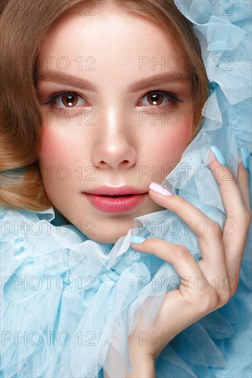 Beautiful girl with light make-up and gentle manicure in blue clothes. Beauty face. Design nails. Photo taken in studio on pink background