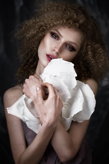 Beautiful girl with curly hair in lingerie with large flower. The beauty of the face. Photos shot in studio