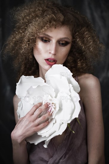 Beautiful girl with curly hair in lingerie with large flower. The beauty of the face. Photos shot in studio