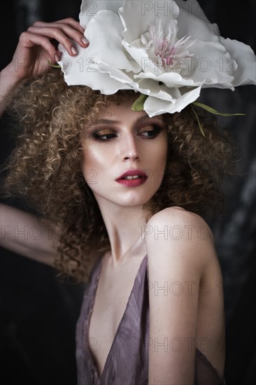 Beautiful girl with curly hair in lingerie with large flower. The beauty of the face. Photos shot in studio