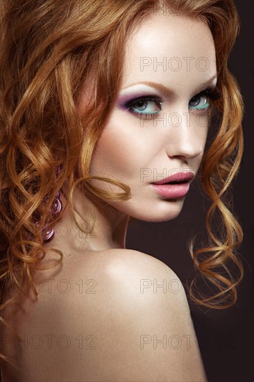 Beautiful red-haired girl with bright makeup and curls. Picture taken in the studio on a black background