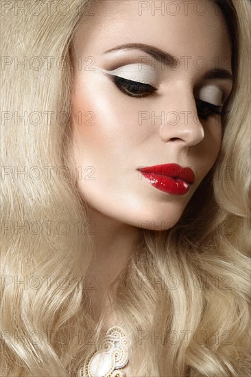 Beautiful blonde woman with evening make-up and red lips. Picture taken in the studio on a black background