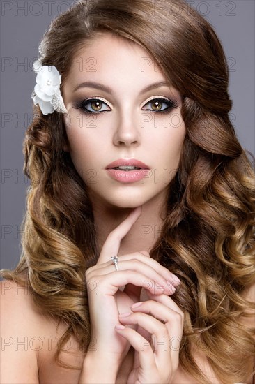 Portrait of a beautiful woman in the image of the bride with flowers in her hair. Picture taken in the studio on a grey background