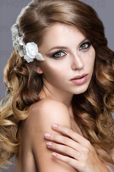 Portrait of a beautiful woman in the image of the bride with flowers in her hair. Picture taken in the studio on a grey background