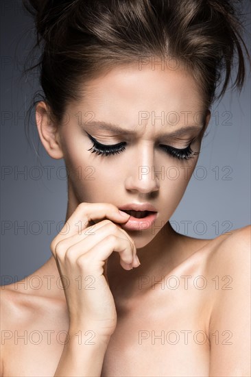 Beautiful girl with long eyelashes and perfect skin. Picture taken in the studio on a gray background. Beauty face