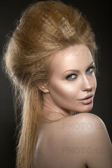 Beautiful red-haired girl with perfect skin and an unusual hairstyle. Picture taken in the studio on a black background