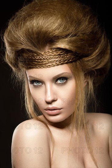 Beautiful red-haired girl with perfect skin and an unusual hairstyle. Picture taken in the studio on a black background