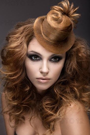 Beautiful woman with evening make-up and hairstyle as a cap of hair. Beauty face. Picture taken in the studio on a gray background