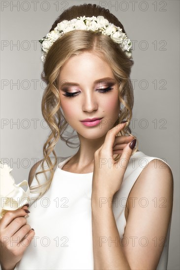 Portrait of a beautiful blond girl in image of the bride with white flowers on her head. Beauty face. Photo shot in the Studio on a grey background