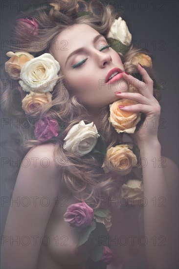 Beautiful girl with a lot of flowers in their hair and bright pink make-up. Spring image. Beauty face. Picture taken in the studio on a grey background