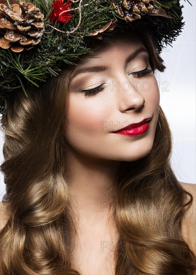 Beautiful girl with a wreath of Christmas tree branches and cones. New Year image. Beauty face. Picture taken in the studio on a white background