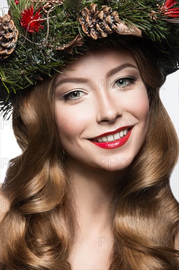 Beautiful girl with a wreath of Christmas tree branches and cones. New Year image. Beauty face. Picture taken in the studio on a white background